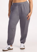A person wears Woolx Parker Sweatpants in Arctic Dusk, standing against a plain white background. Only the lower torso and legs, paired with white sneakers with black stripes, are visible.