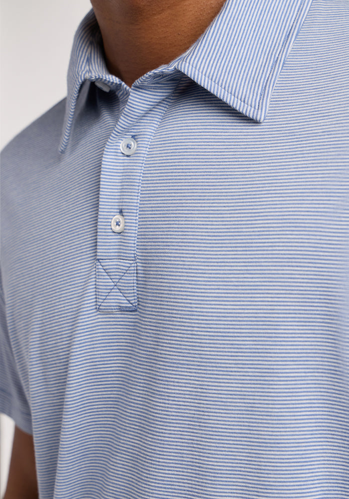 Close-up of a person wearing the Woolx Preston Polo - Blue Sand Mini Stripe, featuring moisture-wicking fabric with light blue and white pinstripes, a collar, and two buttons. Only the lower face, neck, and upper torso are visible.