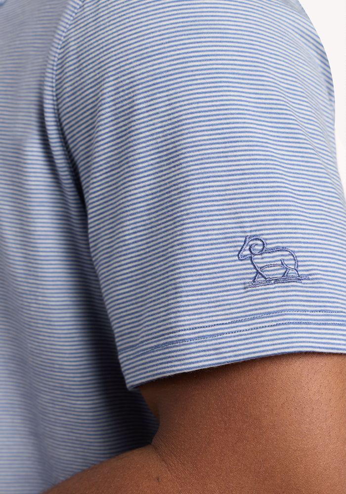 A close-up of a person wearing the Woolx Preston Polo - Blue Sand Mini Stripe, a moisture-wicking shirt featuring thin blue and white stripes and a small embroidered ram outline on the sleeve.