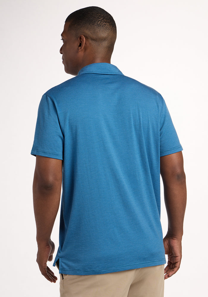 A man stands with his back to the camera wearing the Woolx Preston Polo - Coastal Mini Stripe and beige pants against a plain light background.