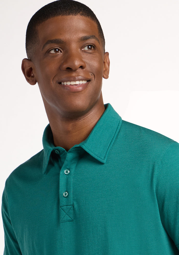 A smiling man wearing a Woolx Preston Polo - Woodland Mini Stripe looks up and to the side against a plain white background.