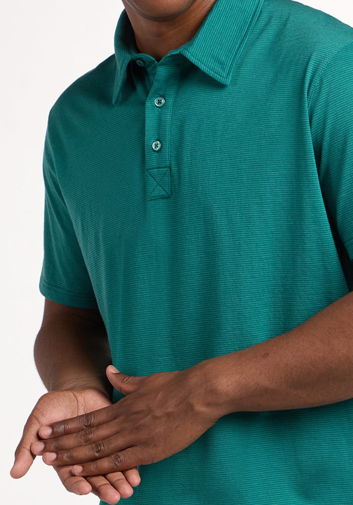 A person is shown from shoulders to waist wearing the Woolx Preston Polo - Woodland Mini Stripe, a short-sleeve shirt with three buttons. Their hands are clasped in front against a plain white background.
