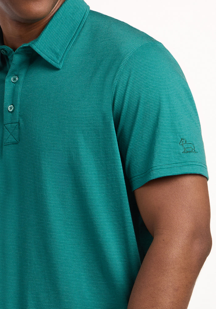A person wearing the Woolx Preston Polo - Woodland Mini Stripe, a moisture-wicking shirt with a ribbed collar and small embroidered logo on the sleeve; only their upper body and part of the right arm are visible.