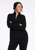 A person with dark hair smiles and gazes to the side while dressed in a black ribbed top and matching pants. With arms crossed in a relaxed manner against a plain white backdrop, they effortlessly exhibit the comfortable elegance of the Woolx Quinn Ribbed 1/4 Zip - Black. | Sarah is 5'8", wearing a size S