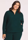 A woman with medium-length brown hair, wearing the Woolx Quinn Ribbed 1/4 Zip in Deep Timber, smiles at the camera against a light background.