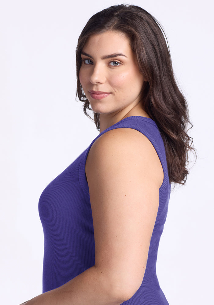 Woman with long brown hair smiles sideways, wearing the Woolx Raegan Ribbed Tank Top in Berry Indigo.