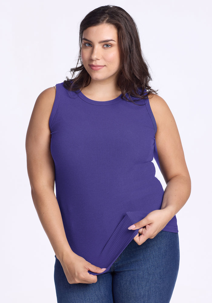 Smiling woman with wavy brown hair wearing Woolx Raegan Ribbed Tank Top in Berry Indigo and blue jeans. | Juliana is 5'10", wearing a size XL