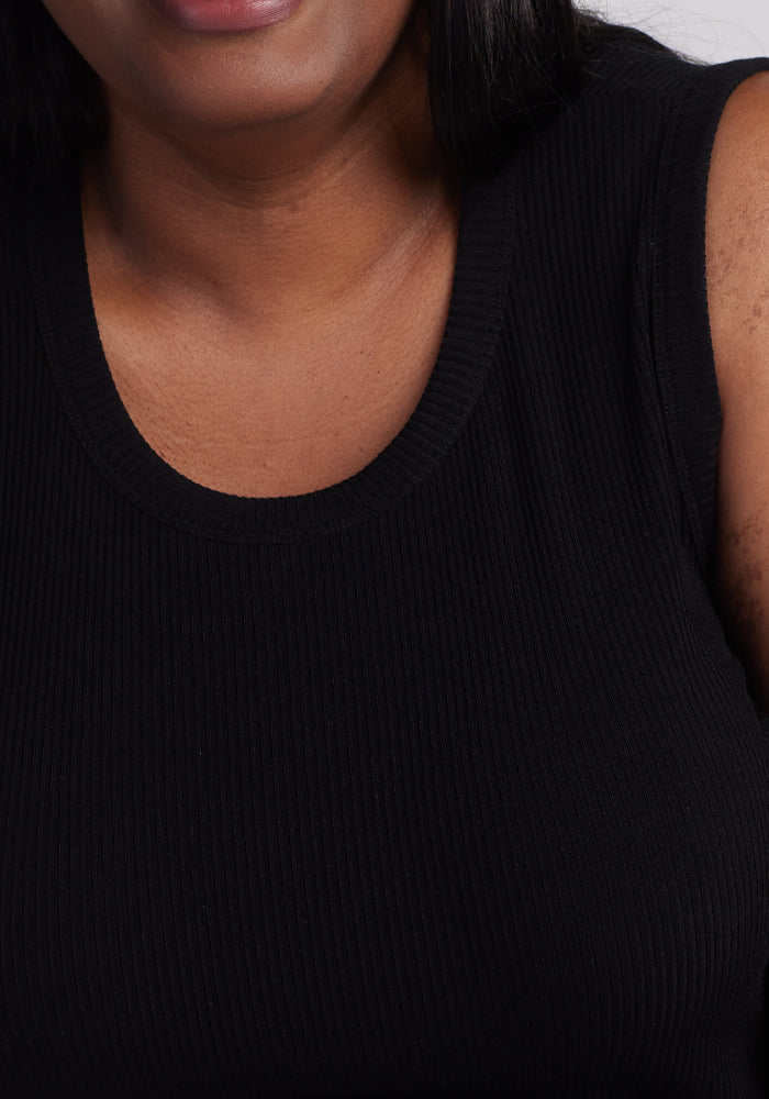 Close-up of a person wearing the Woolx Raegan Ribbed Tank Top in black, with focus on the upper body emphasizing the fabric's rich texture. The person's dark hair contrasts beautifully with the sleek garment.