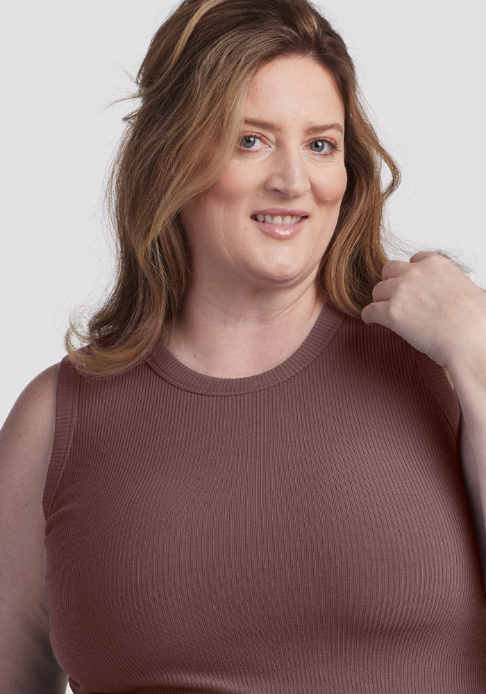 Woman with wavy light brown hair wears the Woolx Raegan Ribbed Tank Top in Peppercorn, smiling at the camera.