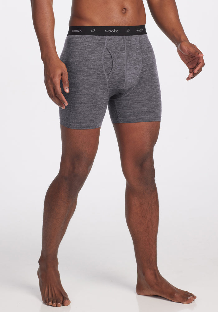 Someone wears the Graphite Heather Reaction Boxer Briefs, featuring a form-fitting design with a black "Woolx" waistband, made from high-performance Merino Wool. The background is plain white.