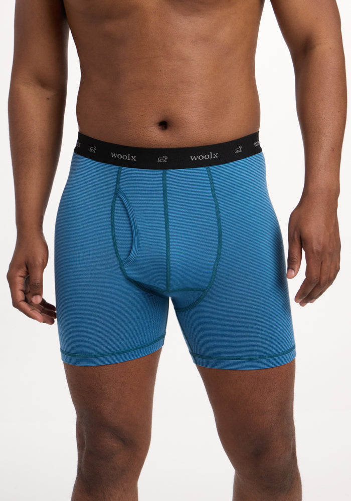 A person models the Woolx Reaction Boxer Briefs in Coastal Mini Stripe, featuring a black "woolx" waistband. The cropped image (shoulders to mid-thighs) against a white background emphasizes the fit of these performance underwear. | Trell is 6’2”, wearing a size M