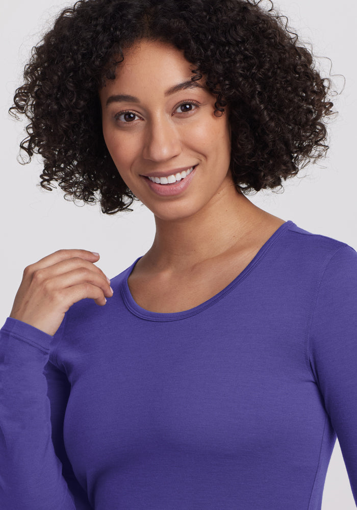 Smiling woman wears Woolx Remi Long Sleeve T-Shirt in Berry Indigo, looking at the camera.