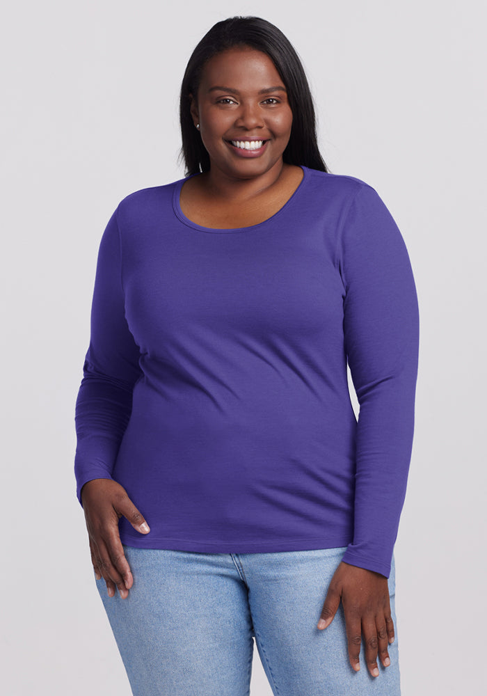 Woman in Woolx Remi Long Sleeve T-Shirt - Berry Indigo and light blue jeans stands against a plain light background. | Le'Quita is 5'11", wearing a size XL