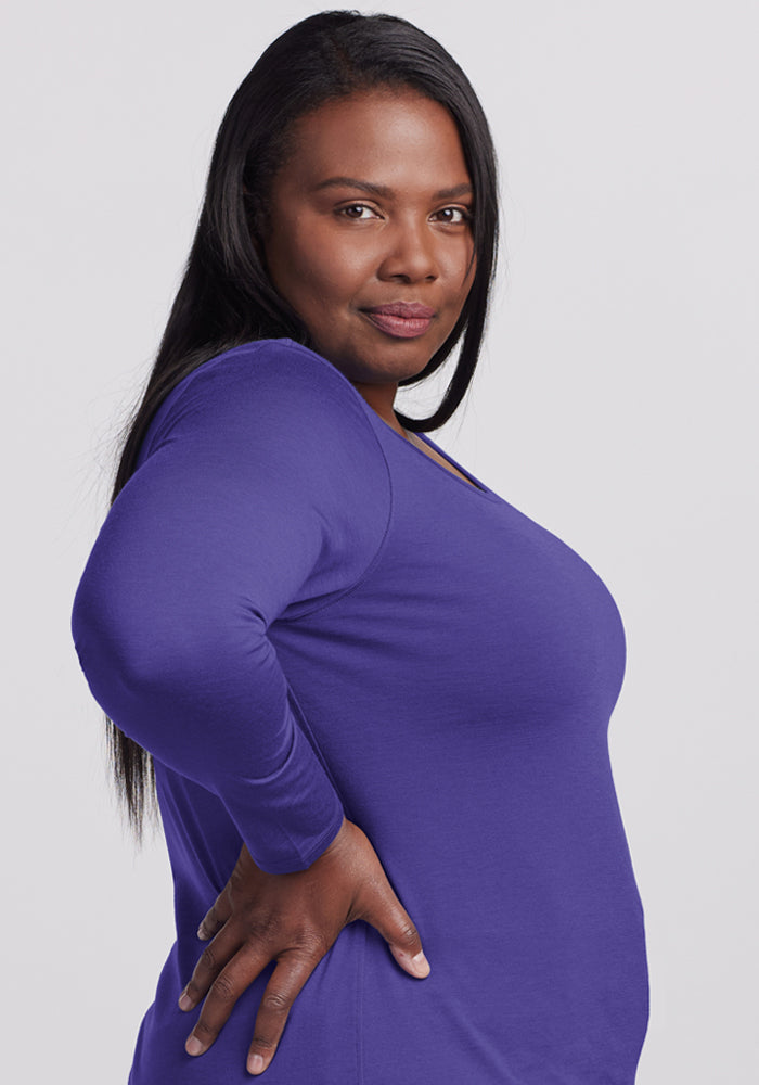 Woman with long dark hair wears the Woolx Remi Long Sleeve T-Shirt in Berry Indigo, smiling confidently.