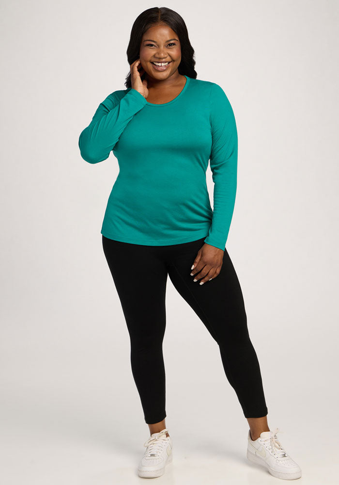 Woman in Woolx Remi Long Sleeve T-Shirt - Cabana Crush, black leggings, and white sneakers poses against a plain background.