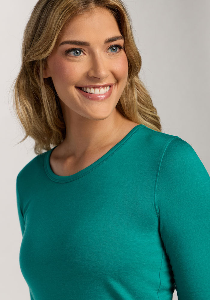 Smiling woman in a Woolx Remi Long Sleeve T-Shirt - Cabana Crush, with wavy blonde hair, facing right.