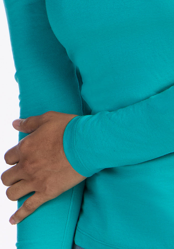 Someone wears the Woolx Remi Long Sleeve T-Shirt in Cool Jade, crossing their arm over their torso.