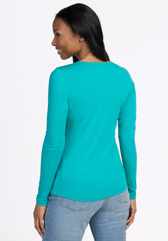 Woman facing away in Woolx Remi Long Sleeve T-Shirt in Cool Jade and light blue jeans against a white background.