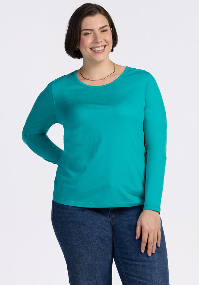 Woman with short brown hair in a Woolx Remi Long Sleeve T-Shirt in Cool Jade and blue jeans, smiling.