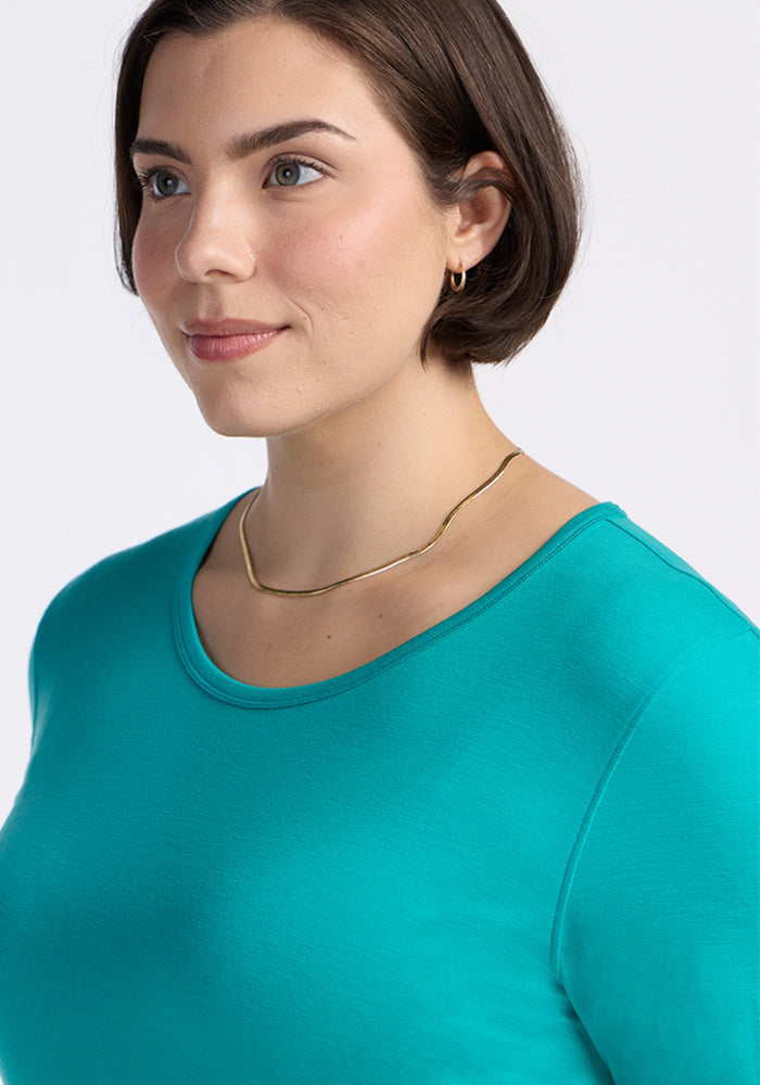 Woman with short brown hair in a Woolx Remi Long Sleeve T-Shirt in Cool Jade, gold necklace, and hoops.