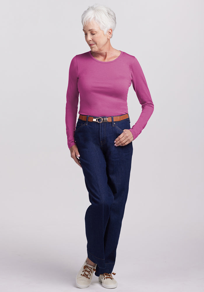 Older woman with short gray hair wears a Woolx Remi Long Sleeve T-Shirt in Purple Wine, standing and looking down.