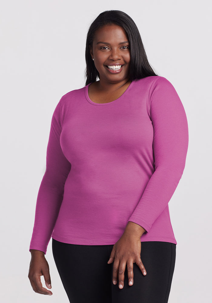 Woman smiling in a Woolx Remi Long Sleeve T-Shirt in Purple Wine and black pants against a light background.