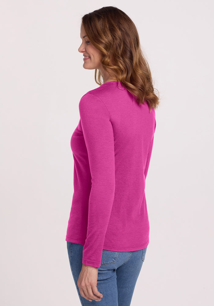 Woman in a Woolx Remi Long Sleeve T-Shirt - Summer Sorbet and jeans, standing sideways and smiling.