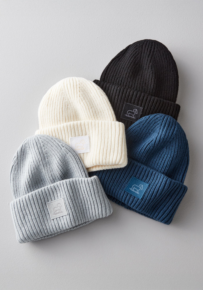 The Woolx Ria Chunky Beanie in black is a cozy ribbed knit winter hat featuring a small rectangular patch with an embroidered animal logo on the front cuff.