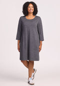 A smiling woman with curly hair wears the Woolx Rissa A Line Dress in Cinder Melange, styled with white sneakers against a light backdrop—ideal for fall/winter layering or as a cozy travel dress. | Maysa is 5’3”, wearing a size M