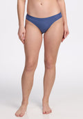 A woman stands barefoot against a plain white background, modeling Woolx Roxie Bikini Underwear in the Skyline color. Her hands are at her sides and her face is not visible in the photo.