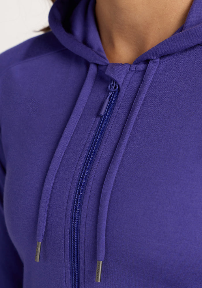 Close-up of a person wearing the Woolx Ryann Hoodie in Berry Indigo with drawstrings and a visible zipper.