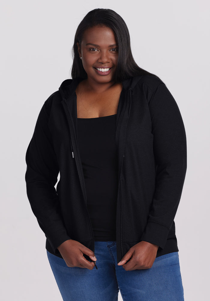 A person smiling, wearing the Woolx Ryann Hoodie in black over a black top and blue jeans, stands against a plain background. | Le'Quita is 5'11", wearing a size XL