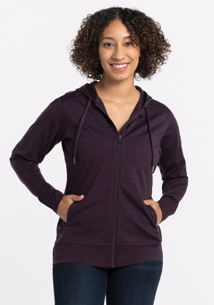 Woman smiling in a Woolx Ryann Hoodie • Final Sale - Deep Plum, hands in pockets, against a plain white background.