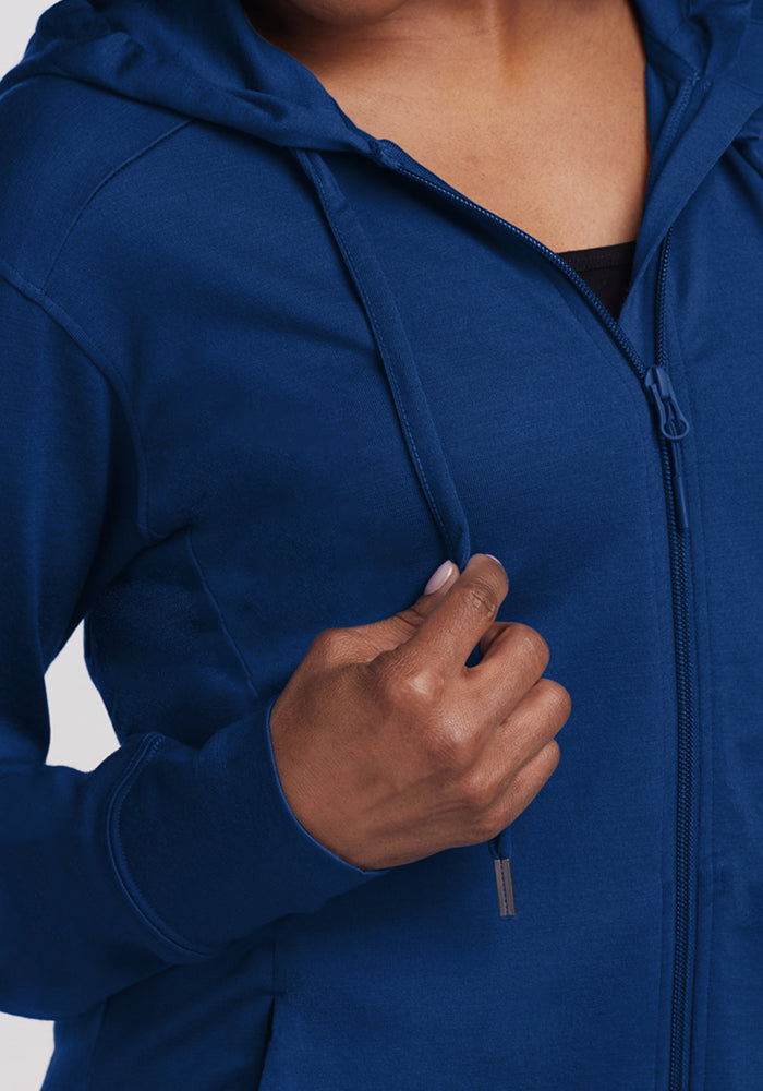 A person wears the Woolx Ryann Hoodie • Final Sale - Estate Blue, holding a drawstring with their right hand.