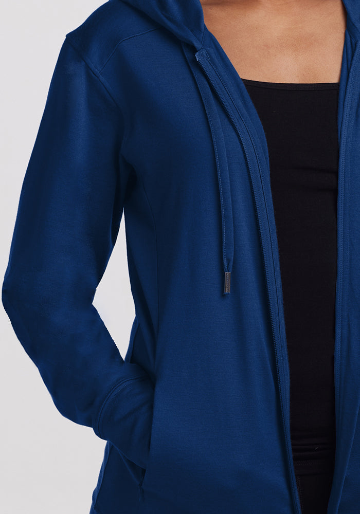 Woolx Ryann Hoodie in Estate Blue—lightweight, worn over a black top with one hand in the pocket; perfect for travel.
