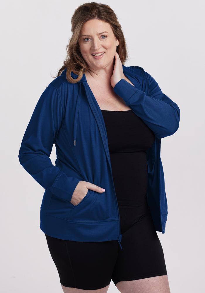 Woman in the Woolx Ryann Hoodie • Final Sale - Estate Blue smiles with hand on neck, wearing a black outfit.