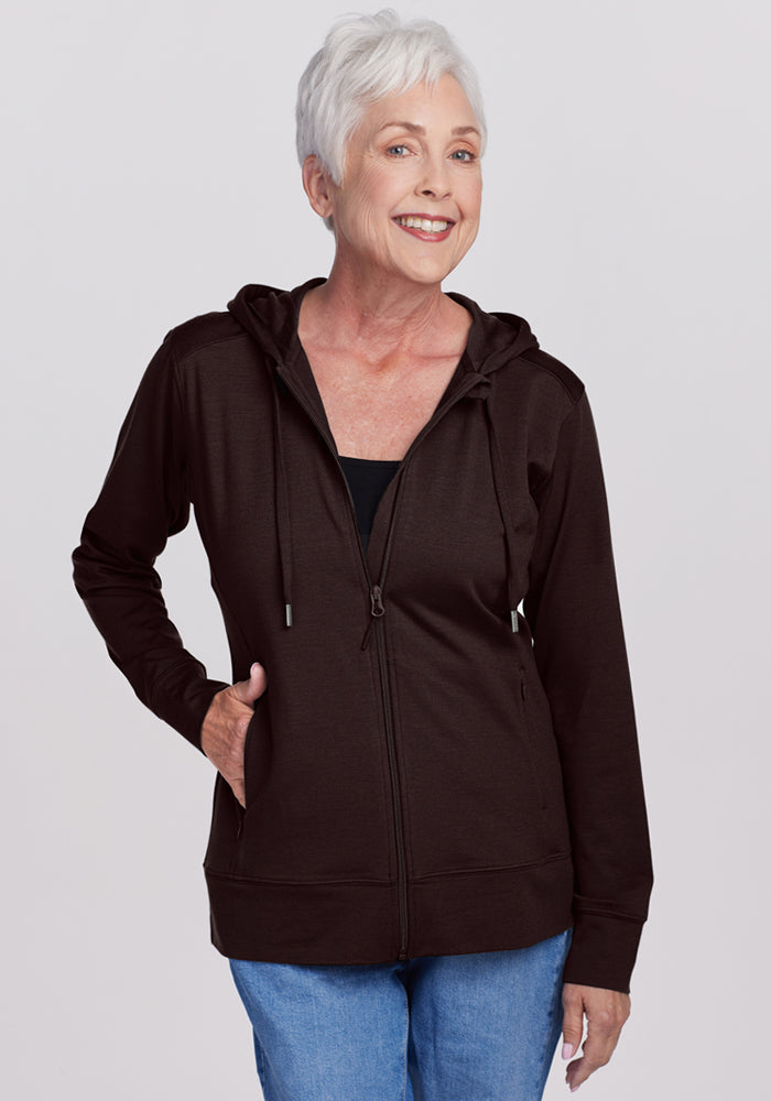 Smiling older woman in a Woolx Ryann Hoodie • Final Sale - French Roast, with blue jeans, against a light background.