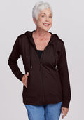 Smiling older woman in a Woolx Ryann Hoodie • Final Sale - French Roast, with blue jeans, against a light background.