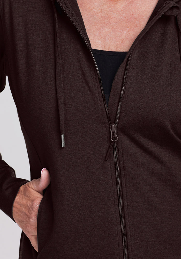 A person wears the Woolx Ryann Hoodie in French Roast, left hand in pocket, black shirt showing underneath.