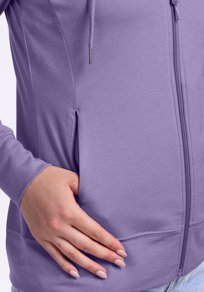 A person rests their hand on the pocket of the Woolx Ryann Hoodie in Montana Grape, paired with light blue jeans.