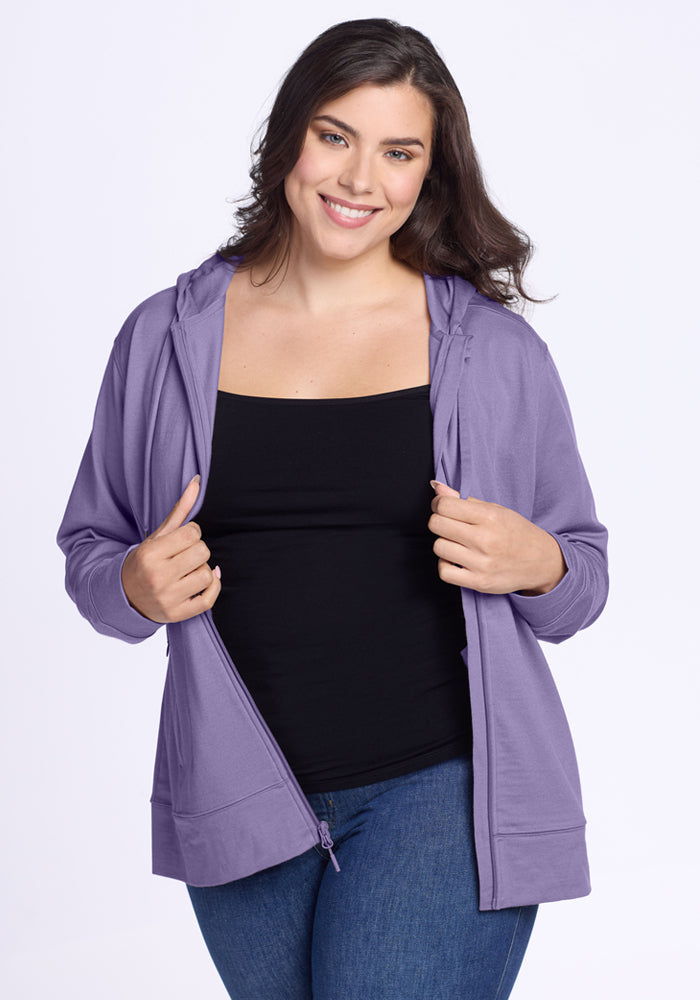 Smiling woman wears Woolx Ryann Hoodie in Montana Grape, black top, and jeans against a white background.