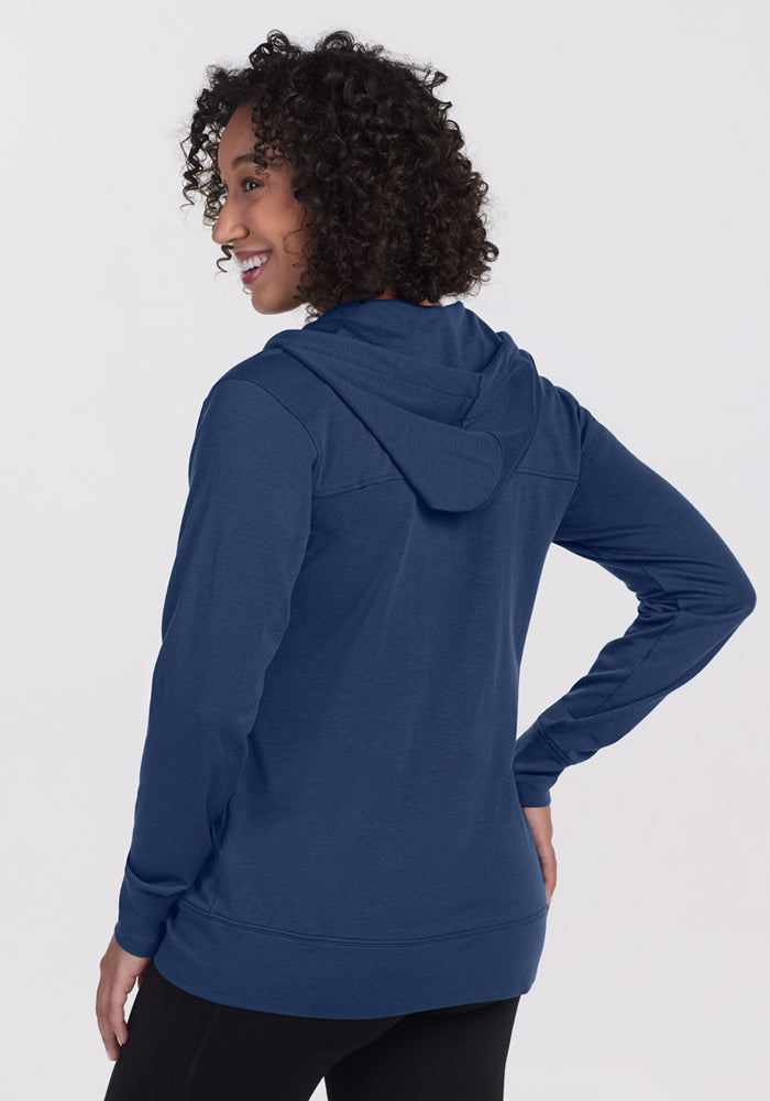 Woman with curly hair in the Woolx Ryann Hoodie in Starry Night, smiling—a true travel essential.
