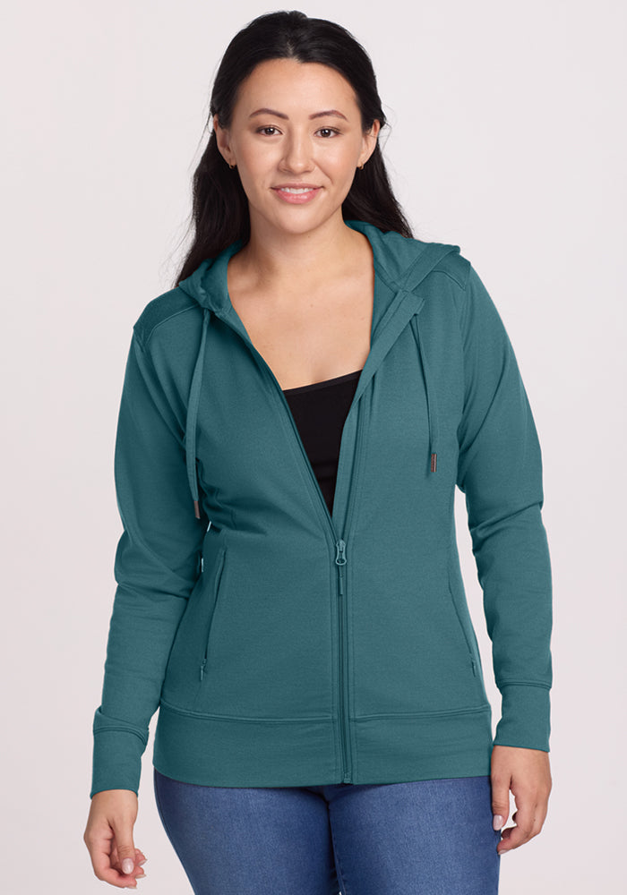 Smiling woman in Woolx Ryann Hoodie (Tidepool), a travel essential—lightweight, teal, perfect for any adventure.