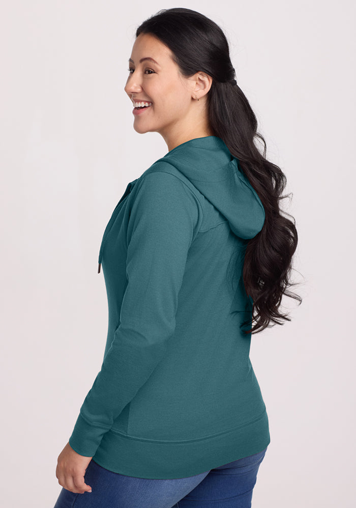 Woman with long dark hair in the Woolx Ryann Hoodie in Tidepool, smiling and looking to the side.