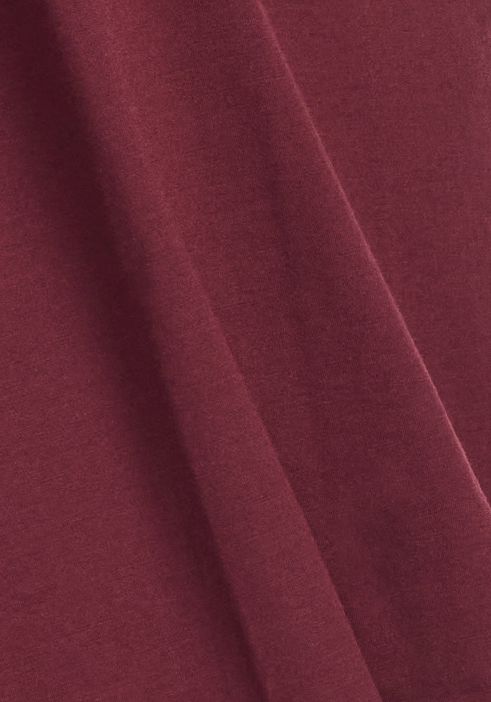 A close-up of Woolx Ryann Hoodie in Toasted Garnet shows soft merino wool folds and a smooth texture.
