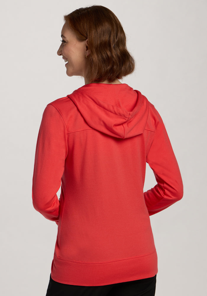 Woman smiles facing away, wearing the Woolx Ryann Hoodie in Hibiscus and black pants against a light background.
