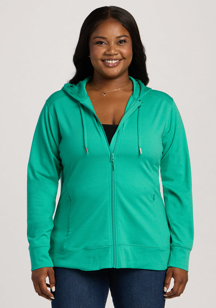 Woman smiling in the Woolx Ryann Hoodie - Jungle, a travel essential, layered over a black top. | Sapphire is 5’8”, wearing a size XL