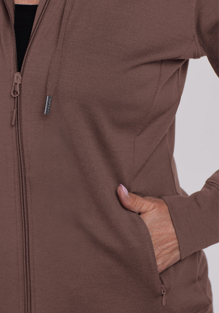 Someone wearing the Woolx Ryann Hoodie in Peppercorn, a moisture-wicking travel essential with a front pocket.