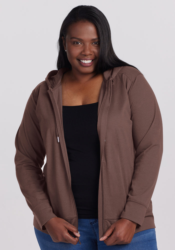 Woman smiling, wearing the Woolx Ryann Hoodie in Peppercorn over a black top and blue jeans—a true travel essential. | Le’Quita is 5’11”, wearing a size XL