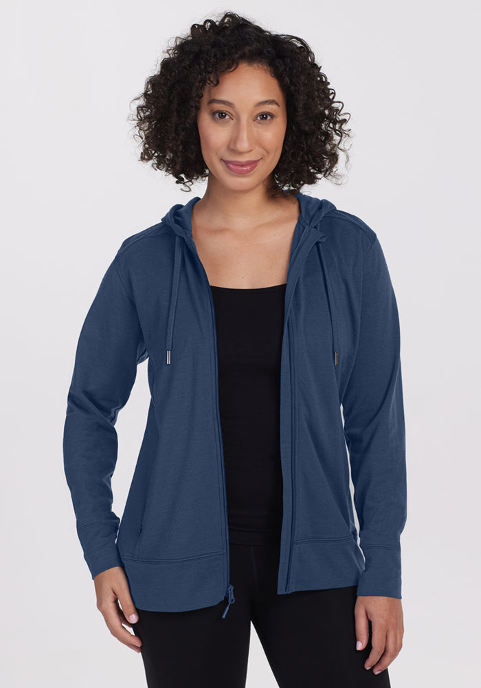 A woman wearing the Woolx Ryann Hoodie in Starry Night—a blue, moisture-wicking merino wool essential for travel.